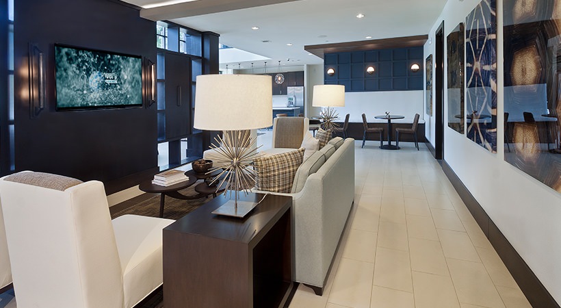 the lobby of a modern apartment building with a large television at The Live Oak at  Branch